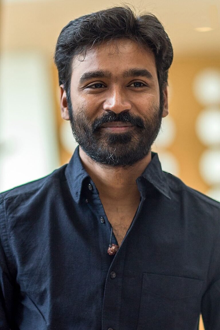 "Actor Dhanush smiling during his 42nd birthday celebration, highlighting his journey from local star to global icon."