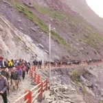 "A symbolic mountain trail in Kashmir with pilgrims turning back due to a blocked path, representing the suspension of the Amarnath Yatra amid scenic snowy peaks and warning signs indicating track maintenance."